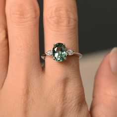 a woman's hand with a ring on it and a green stone in the middle