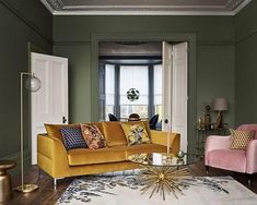 a living room with green walls and yellow couches in the corner, along with a rug on the floor