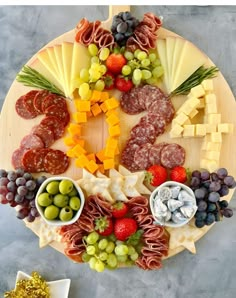 a platter with cheese, meats and fruit arranged in the shape of a circle