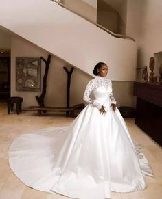 a woman in a white wedding dress standing on the floor next to a stair case