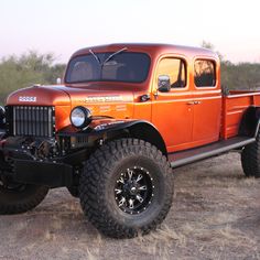 an orange truck parked on top of a dirt field