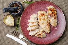 a plate that has some chicken on it next to utensils and seasoning