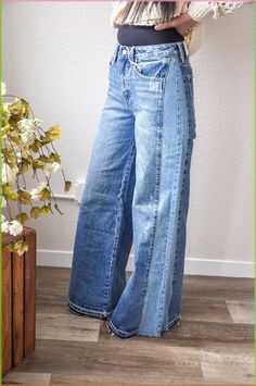 a woman standing in front of a plant wearing high waist jeans