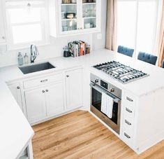 a white kitchen with an oven, sink and countertop area in it's center