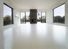 an empty room with large windows and a fireplace