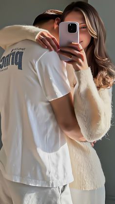 a man and woman taking a selfie in front of a mirror with their cell phones