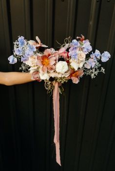 a bridal bouquet with blue and pink flowers on it's headpieces