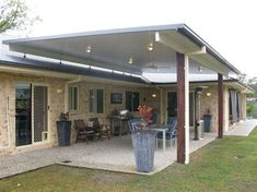 an outdoor patio with table, chairs and grill on the back side of the house