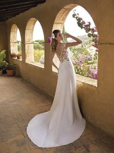 a woman in a wedding dress leaning against a wall with her hand on her head