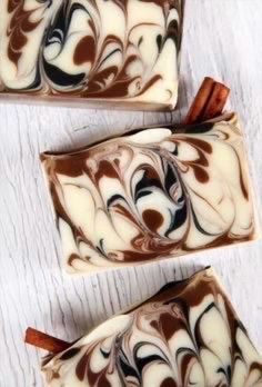 three pieces of chocolate and caramel swirled soap on a white surface with cinnamon sticks