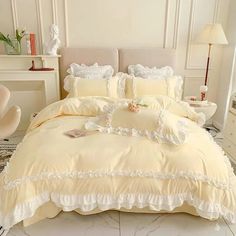 a bed with white comforter and pillows in a large room next to a mirror