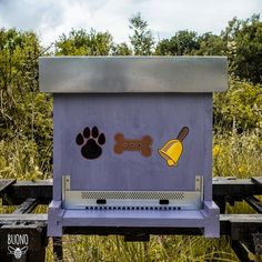 a purple dog kennel with paw prints on the front and side, along with a yellow shovel