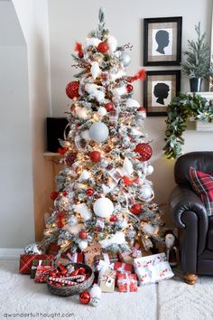 a decorated christmas tree in a living room with red and white ornaments on the top