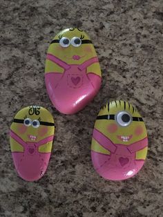 three pink and yellow painted rocks with eyes