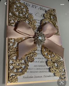 a wedding card with a pink ribbon and a jeweled brooch on the front