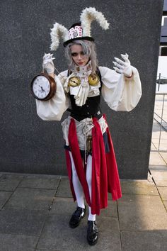 a woman dressed in costume holding a clock