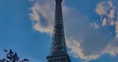 the eiffel tower towering over trees and clouds