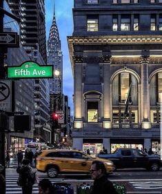 people are crossing the street in front of an old building with a sign that says fifth ave