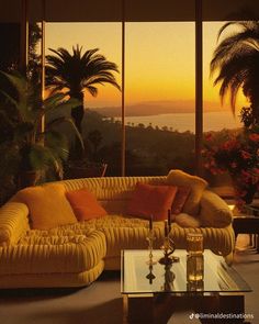 a living room filled with furniture and large windows overlooking the ocean at sunset or sunrise