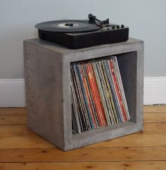 a concrete record player stand with records in it