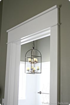 a light fixture hanging from the ceiling in a room with white walls and trim around it