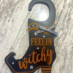 a wooden sign with the words feelin'witchy on it and a pair of scissors