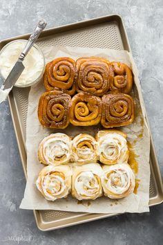 cinnamon buns on a baking sheet with cream cheese