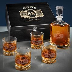 four whiskey glasses and an empty bottle in front of a box with the same label on it