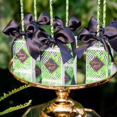 there are four small boxes with black bows on top of the cake stand, and tied in ribbons