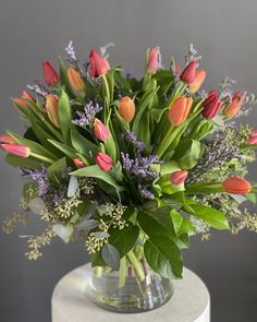 a vase filled with lots of flowers sitting on top of a white tablecloth covered pedestal