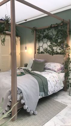 a bedroom with a bed and plants on the headboard, in front of a green wall