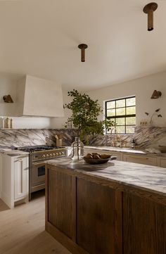 a kitchen with marble counter tops and wooden cabinets, along with an island in the middle