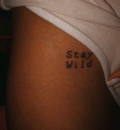 a woman's stomach with the words stay wild written on it in cursive font