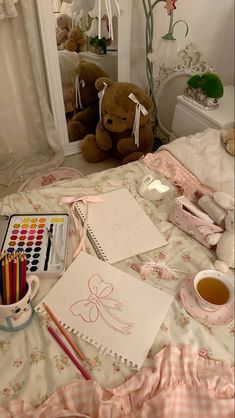 a teddy bear sitting on top of a bed next to a table with markers and pencils