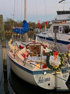 a sailboat is decorated with christmas lights and wreaths for the holiday season, along with other boats