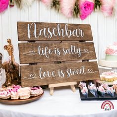 a wooden sign sitting on top of a table next to cakes and cupcakes