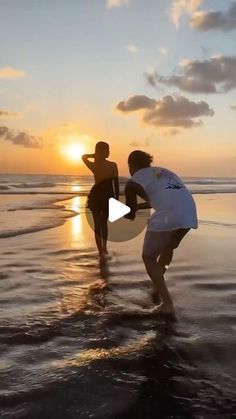 two people are standing in the water at sunset