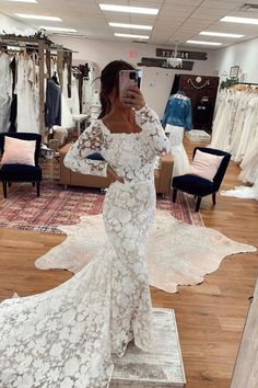 a woman taking a selfie in a wedding dress shop with her phone up to her ear