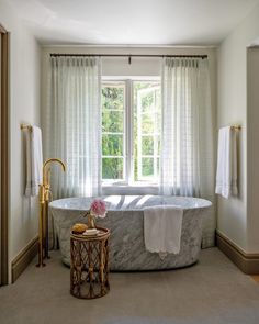 a bathroom with a large marble bathtub next to a window