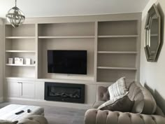 a living room filled with furniture and a flat screen tv mounted on a wall above a fire place