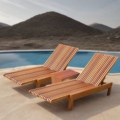 two wooden lounge chairs sitting next to a swimming pool