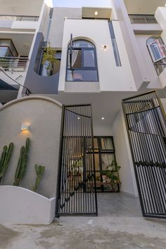 an entrance to a modern apartment building with cactus in the foreground and metal gated entry way