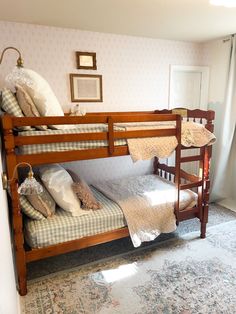 a bunk bed with pillows and blankets on it in a room next to a window