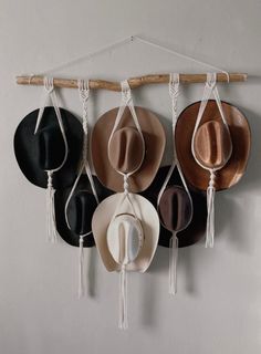 four hats hanging on a wall with rope