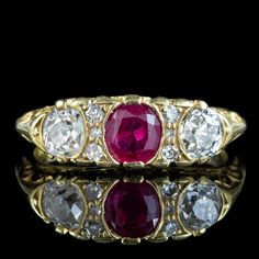 A gorgeous Victorian style carved half-hoop ring set with a bright natural pink ruby in the centre (approx. 0.65ct) flanked by sparkling old mine cut diamonds on either side (approx. 0.25ct each) and four smaller diamonds nestled in between. (approx. 0.60ct total).  Ruby is the birthstone of July. They've been a favourite of kings and emperors throughout history and are considered a stone of the heart. Its fiery pink/ red hue is symbolic of passion and said to bring good fortune in love and prov Heirloom Three Stone Ruby And Diamond Ring, Heirloom Three Stone Ruby Ring With Diamonds, Heirloom Three-stone Ruby And Diamond Ring, Heirloom Three-stone Ruby Ring With Diamonds, Antique Ruby Ring With Single Cut Diamonds, Pink Ruby Ring With Rose Cut Diamonds, Pink Ruby Ring With Single Cut Diamonds, Vintage Pink Ruby Ring With Diamonds, Vintage Pink Diamond Ruby Ring