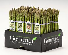 several bundles of asparagus sitting in a black cardboard box with labels on them