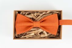 "Orange wedding bow tie for men, boy or baby / Eco frienldy linen orange bow tie for groom Details Material - 100% Linen. Pre-Tied Bow Tie. Handmade - Made To Order. Packaged in a gift box. Bow Tie Sizes Pre tied Adult bow tie: Attached to an adjustable strap fitting approx 13 inch - 19 inch neck size Bow tie size - Width: 12cm / 4,7\" | Height: 6cm / 2,4\" (For 17 yrs up to adult's) Pre tied Youth bow tie: Attached to an adjustable strap fitting approx 10 inch - 15 inch neck size Bow tie size - Satin Bow Tie As Summer Gift, Summer Bow Tie Back Tie As A Gift, Summer Bow Tie Back Ties As Gift, Summer Gift Bow Standard Tie, Summer Gift Standard Tie Bow, Dapper Bow Tie For Summer, Summer Bow Ties As Gifts, Orange Bow Tie, Bow Tie For Men