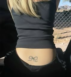 a woman with a bow tattoo on her lower back and the upper half of her stomach