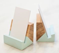 two wooden business cards are placed next to each other on a white surface with light blue accents