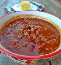 a red bowl filled with soup next to a piece of cake on a table top